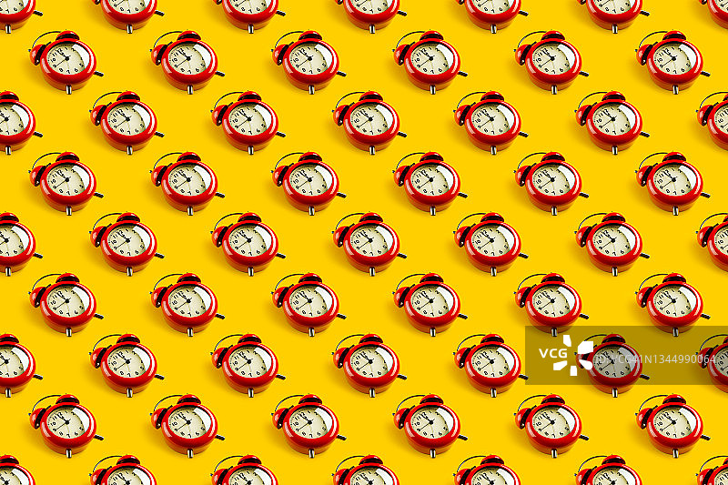 明亮黄色背景上的红色复古闹钟：时间流逝的概念图片素材