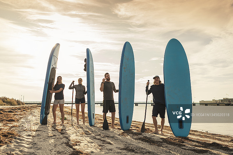 海滩度假时携带桨板的男女友人肖像图片素材