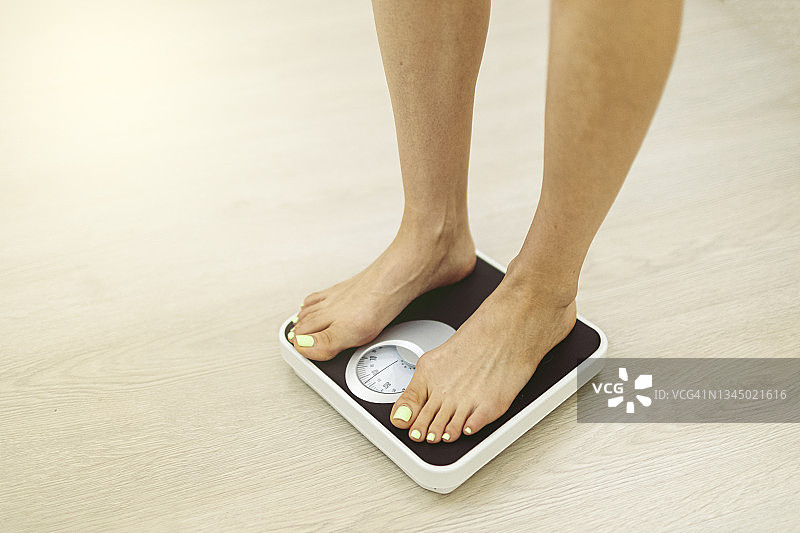 赤脚女子在体重秤上测量体重图片素材