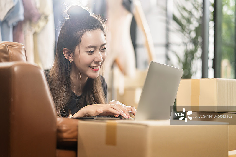 亚洲女性 மகிழ்ச்சியுடன் 微笑，通过笔记本电脑进行客户订单录入，电子商务和在线购物，亚洲女性在线服装店主在家庭工作室愉快地工作图片素材