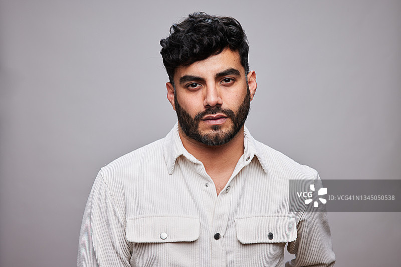 自信时尚的年轻人站在灰色背景前图片素材