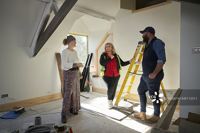 女建筑工人在阁楼建筑工地与另一位建筑工人及客户讨论项目图片素材
