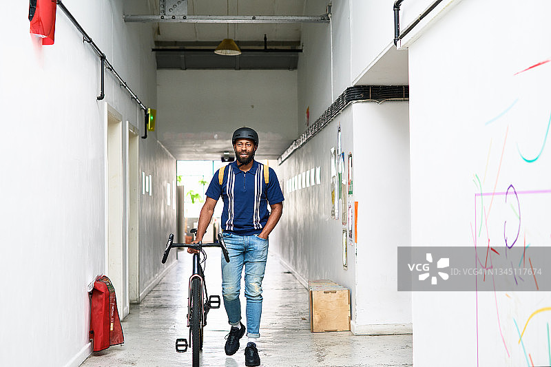 中年男人推着自行车穿过走廊图片素材