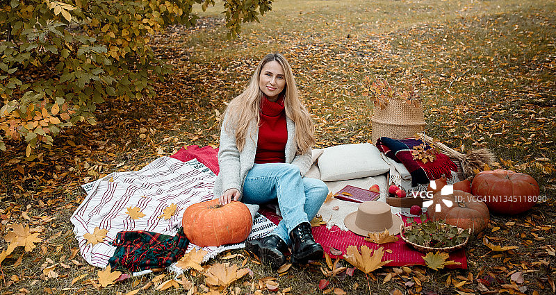 年轻白人女性在秋季野餐时与南瓜合影图片素材
