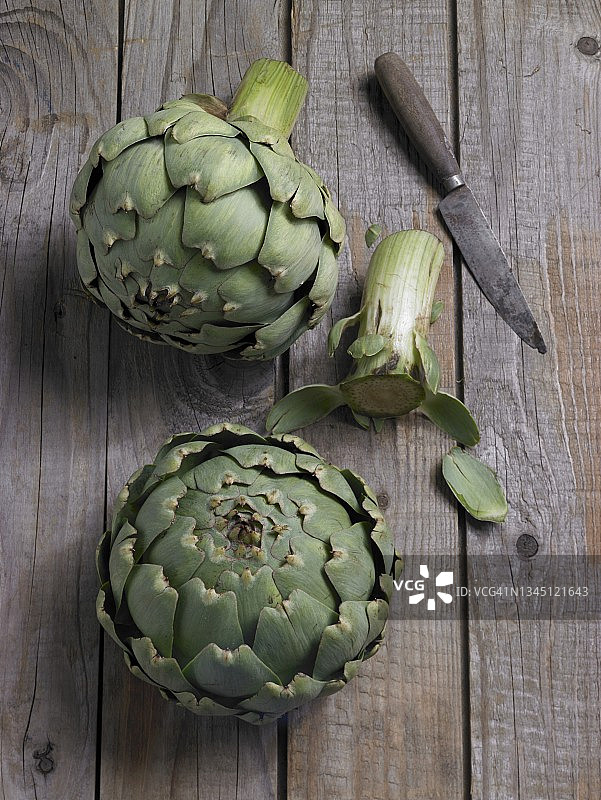 两颗新鲜朝鲜蓟与刀具，木质背景图片素材