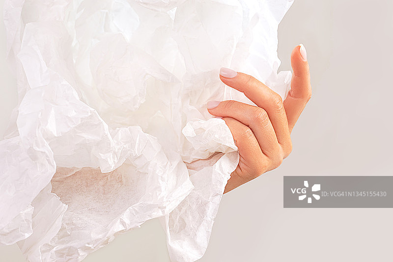 漂亮女人手持白色皱纸，背景为潮流灰色水滴色。抽象文本模板。图片素材