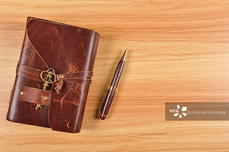 复古办公桌，配有复古皮革笔记本和钢笔，顶部视角图片素材