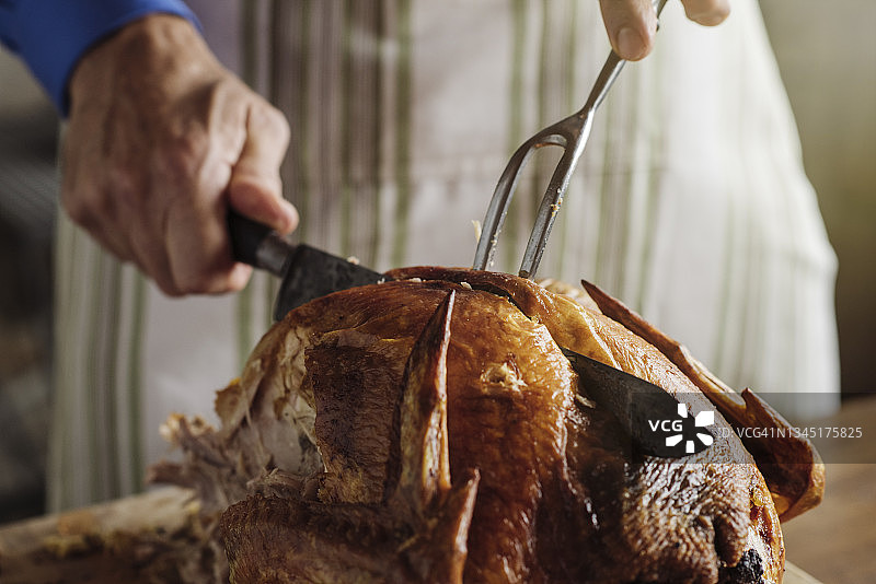 年长男人在感恩节用刀雕刻烤火鸡图片素材