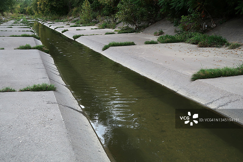 沿着笔直的混凝土河道流淌的河流图片素材