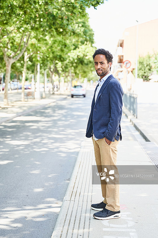 男子站在街边，双手插在口袋里侧视图图片素材