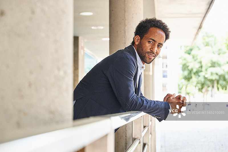 等待朋友共进午餐时对着镜头微笑的年轻商人图片素材