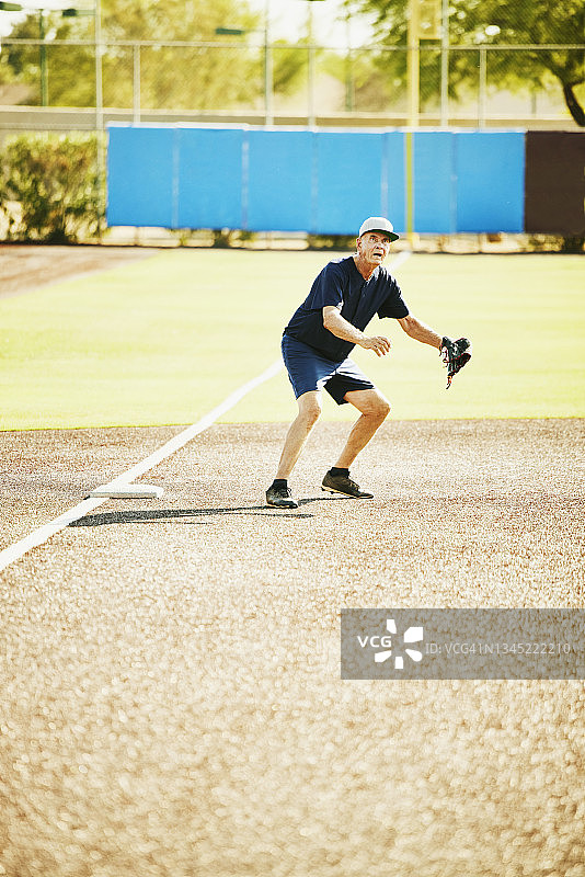 夏日清晨，年长的垒球内场手准备接高飞球图片素材
