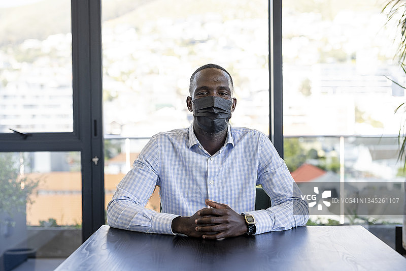 戴口罩坐在会议室里的年轻非洲商人肖像图片素材