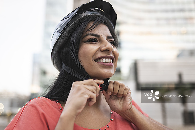 在城市里戴自行车头盔微笑的漂亮女人图片素材