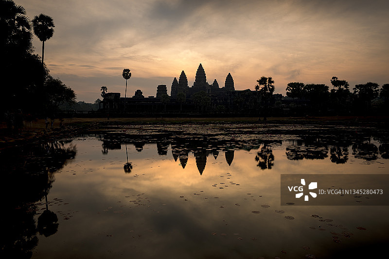 柬埔寨暹粒：日出时分，在水面上看到的吴哥寺剪影图片素材