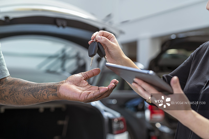 手持汽车钥匙与数字平板图片素材