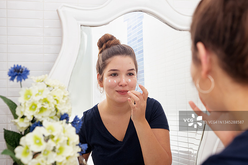 女人在晨间护理时往脸上涂抹保湿霜图片素材