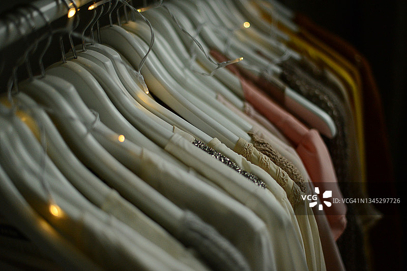 不同颜色的衬衫和毛衣挂在衣架上，按颜色排列图片素材