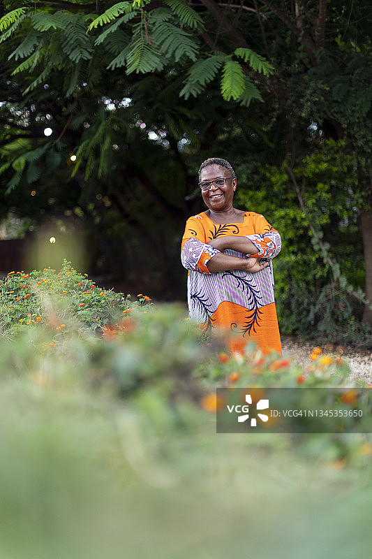 自信的非洲妇女肖像站在花园双臂交叉图片素材