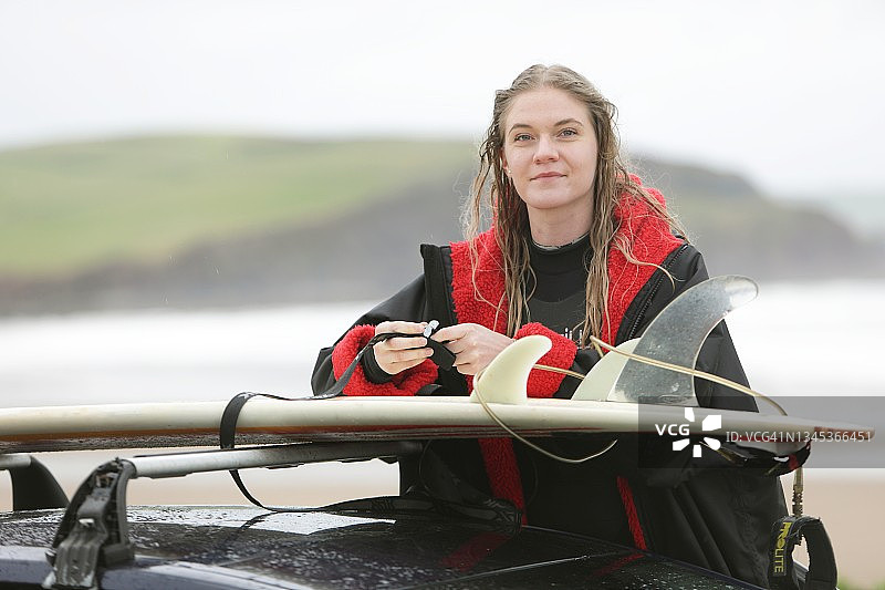 女人将冲浪板绑在车顶上图片素材