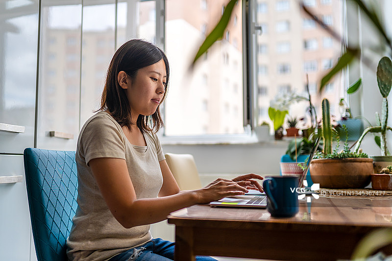 在家用笔记本电脑工作的年轻亚洲女性图片素材