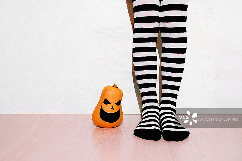 万圣节南瓜与条纹袜女孩腿部的特写镜头图片素材