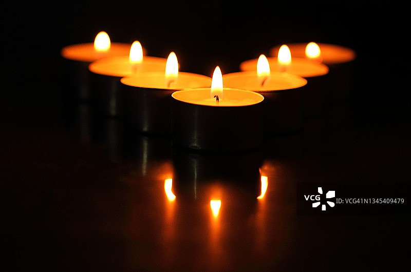 黑暗中带有3个倒影的7支蜡烛图片素材