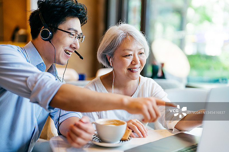 亚洲妇女与年轻男子有视频通话笔记本电脑。图片素材