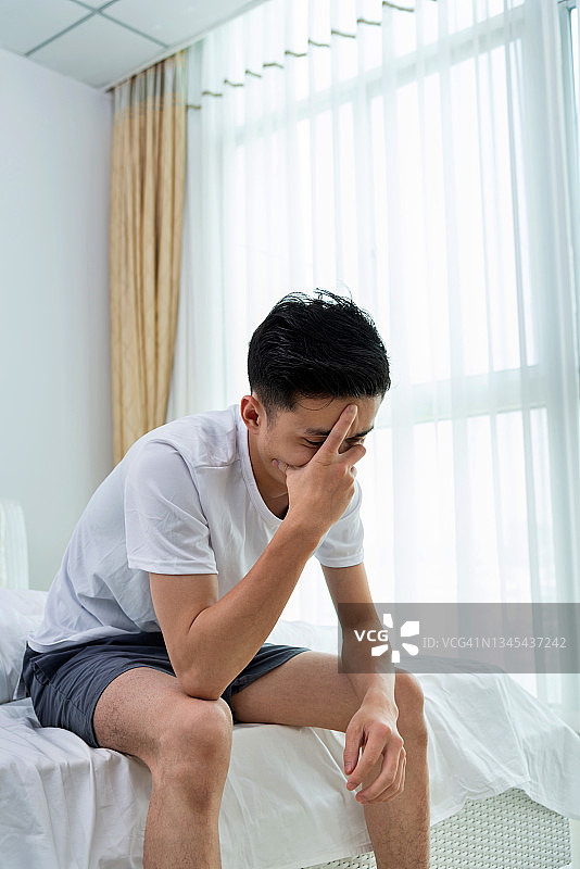 年轻男人坐在床上遮住脸图片素材