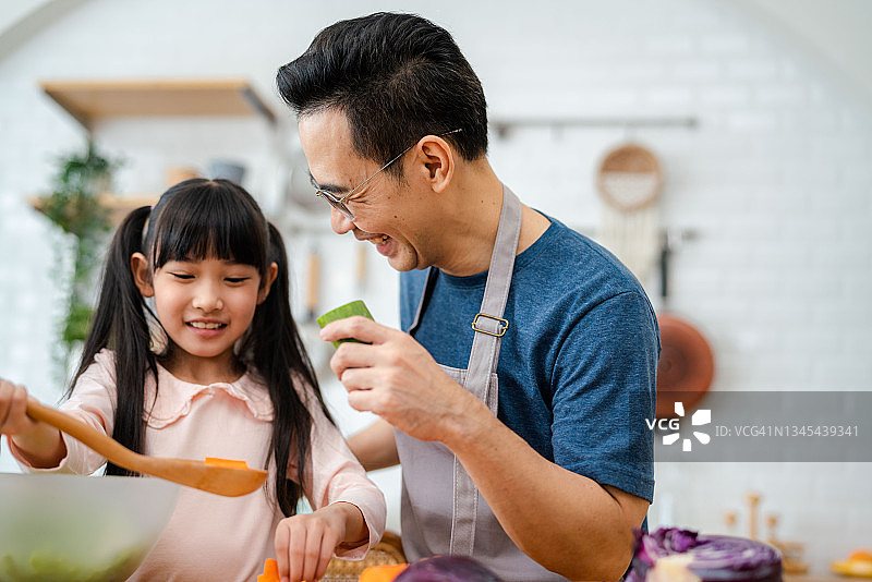 父亲和孩子一起在家做饭。图片素材