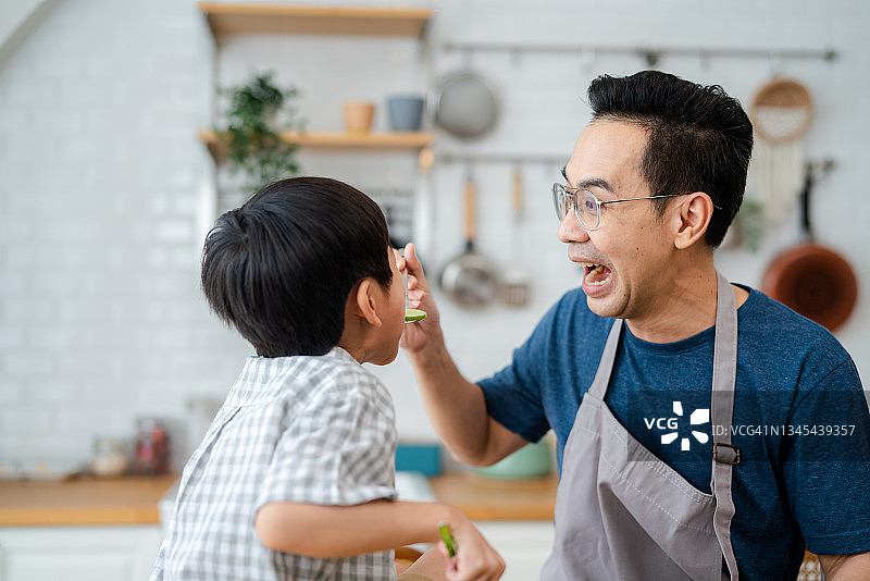 父亲和孩子一起在家做饭。图片素材