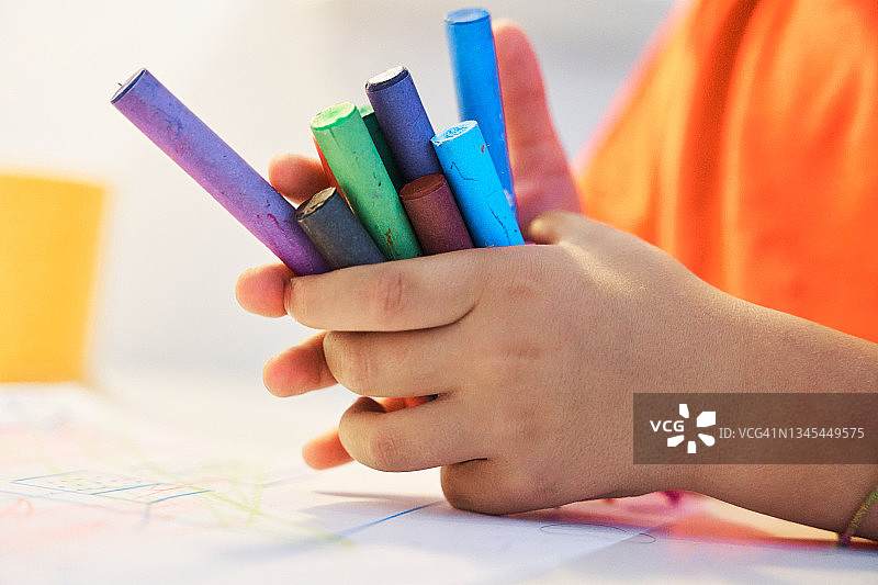 小孩双手拿着蜡笔的特写镜头图片素材