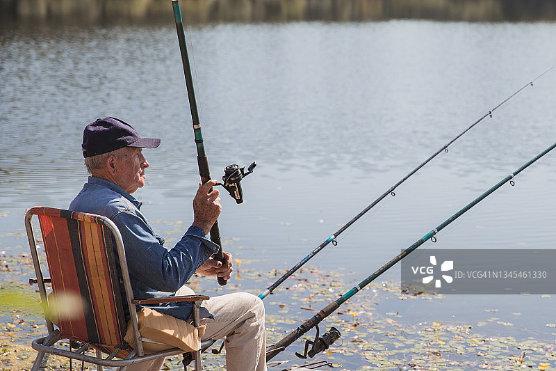 渔民坐在户外椅上使用钓鱼竿图片素材