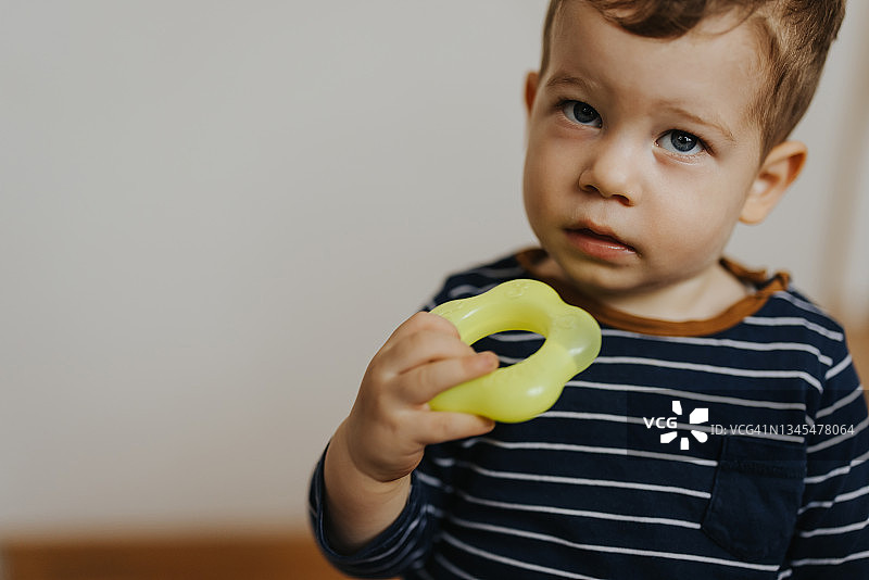 可爱小男孩肖像，手持磨牙玩具，在家图片素材