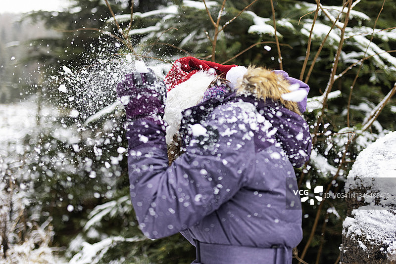 戴着圣诞帽的少女在圣诞节享受雪仗图片素材