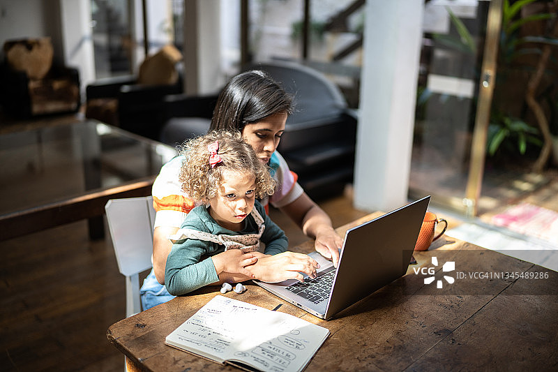 母亲在家中抱着女儿使用笔记本电脑图片素材