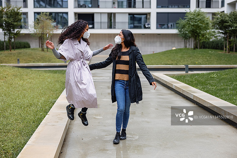 两个女人在公寓楼外散步微笑图片素材