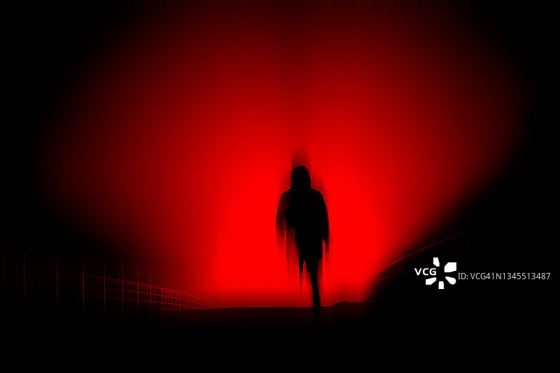 黑暗恐怖概念：夜间灯光下模糊的蒙面人轮廓图片素材
