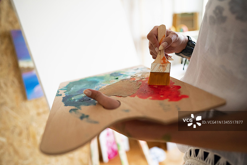 女艺术家拿着木制调色板，混合油画颜料图片素材