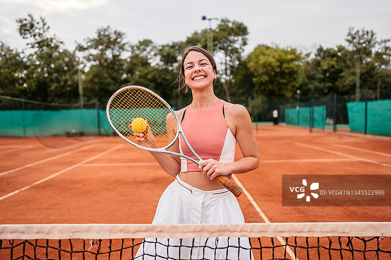 在网球场上拿着球和球拍的微笑女人图片素材