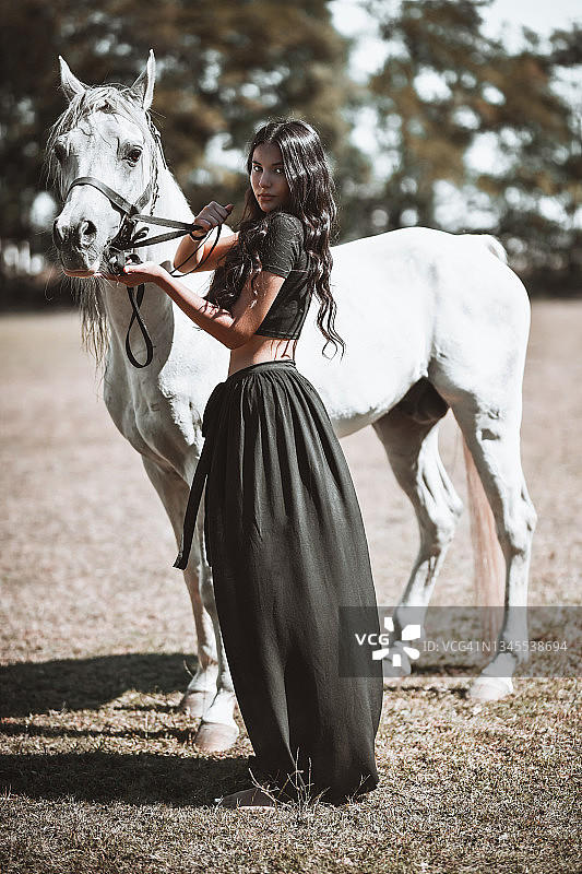 青少年吉普赛女孩在牧场牵着马图片素材