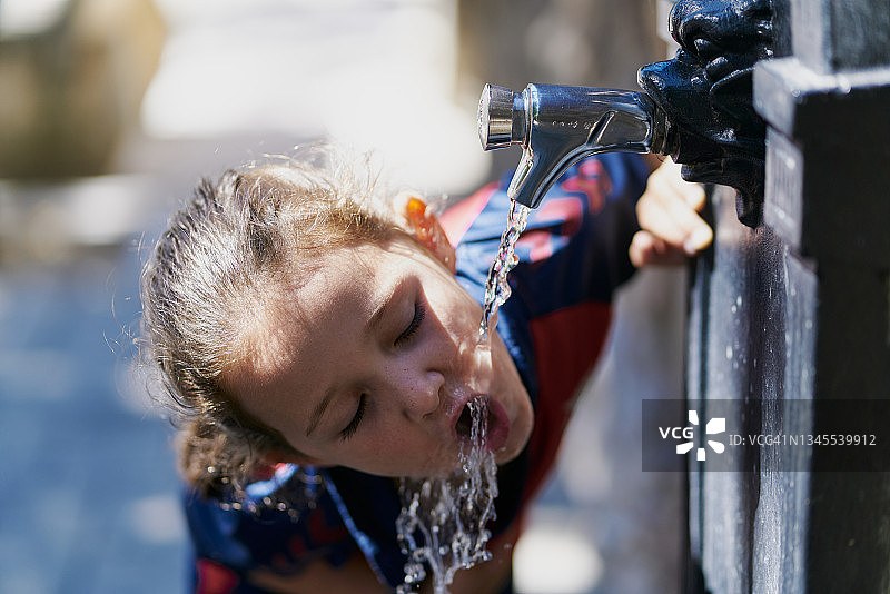 小女孩在西班牙街头饮水机喝水图片素材
