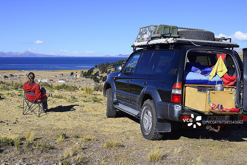 在的的喀喀湖，普诺省，秘鲁，咖啡休息期间，在改装成露营车的越野车旁的女人图片素材