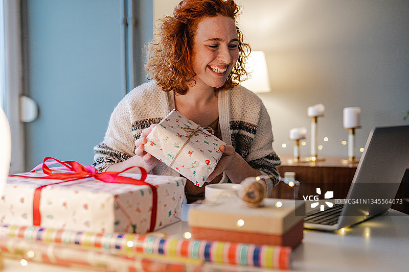 年轻女人在家观看在线创意并包装圣诞礼物图片素材