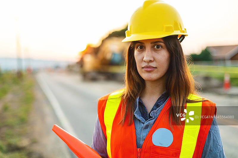 关注拉美裔工人在街道公路施工现场设置障碍和指挥交通图片素材