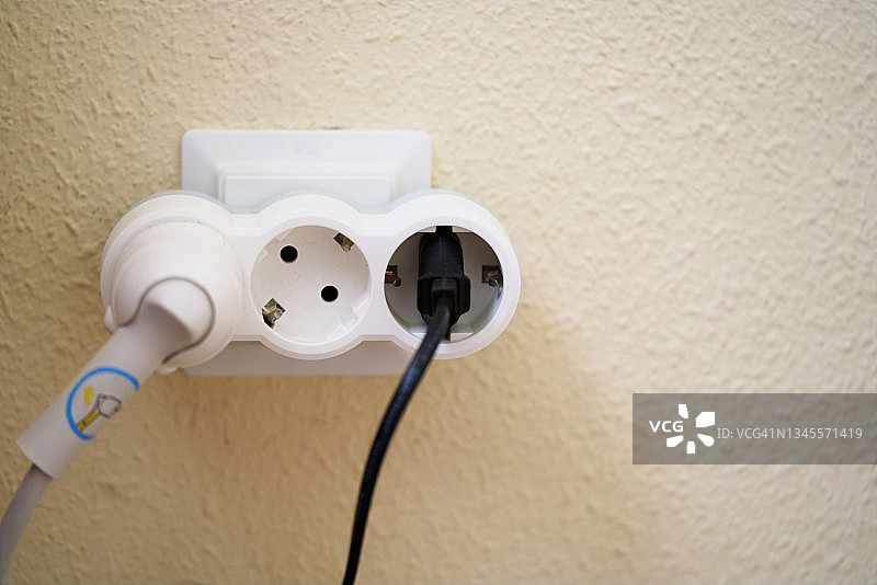 墙壁上的白色电源插座连接着两个插头图片素材