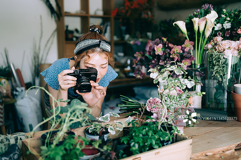 年轻的亚洲女花店主，拍摄各种花卉植物，更新并发布到她的网上商店，并在网上销售产品。经营网上业务，电子商务，使用科技进行网上购物图片素材