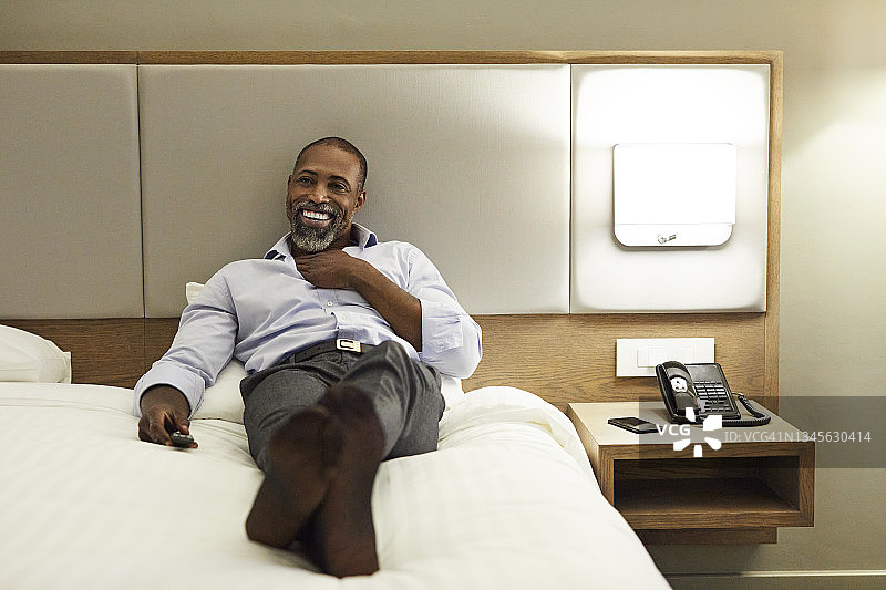 躺在酒店里看电视的企业家图片素材