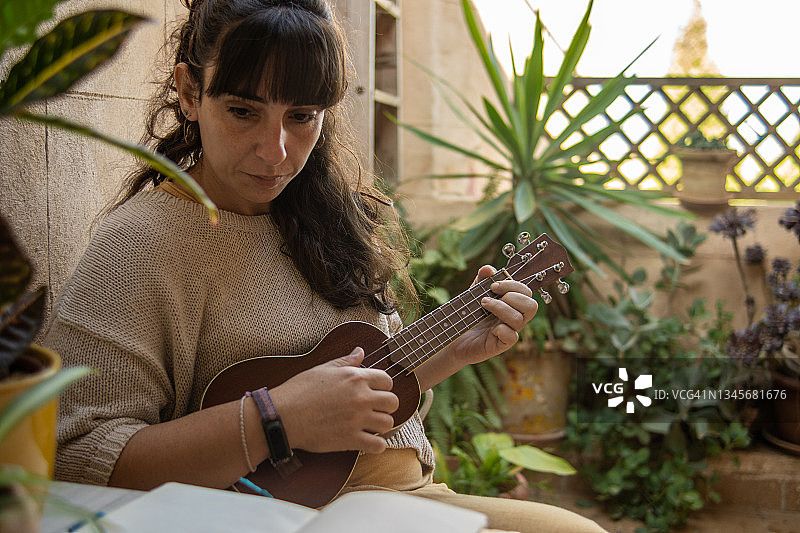 年轻的拉丁裔女人在后院练习尤克里里图片素材
