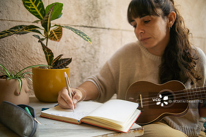 女作曲家坐在房子的露台上，灵感迸发，用她的尤克里里写歌图片素材
